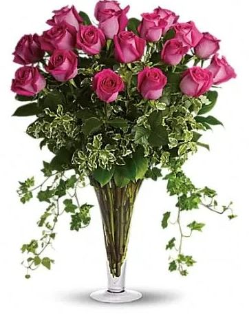 Bouquet of pink roses in a clear glass vase with trailing ivy