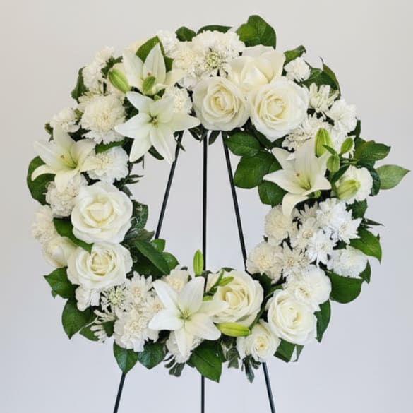 Serenity Wreath - A ring of fragrant, bright white blossoms will create a serene display at any funeral or wake. This classic wreath is delivered on an easel, and is a thoughtful expression of sympathy and admiration. A standing wreath created from fresh white flowers such as roses, Asiatic lilies, carnations and cushion spray chrysanthemums - accented with greenery - is delivered on an easel. 