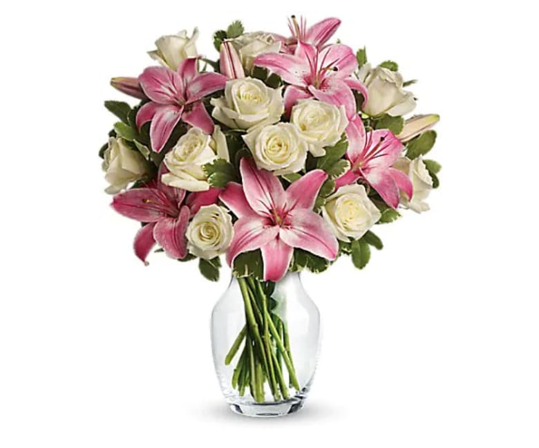 Pink lilies and white roses arranged in a clear glass vase