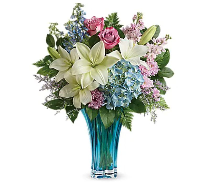 Bouquet of lilies, roses, and hydrangeas in a blue glass vase