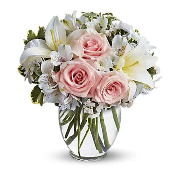 Pink roses and white lilies arranged in a clear glass vase