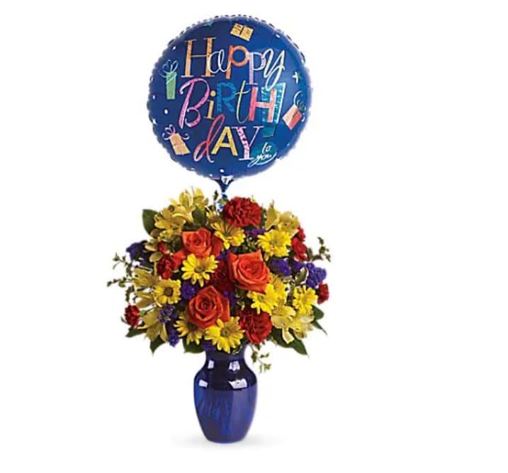 Birthday balloon above a colorful flower arrangement in a blue vase