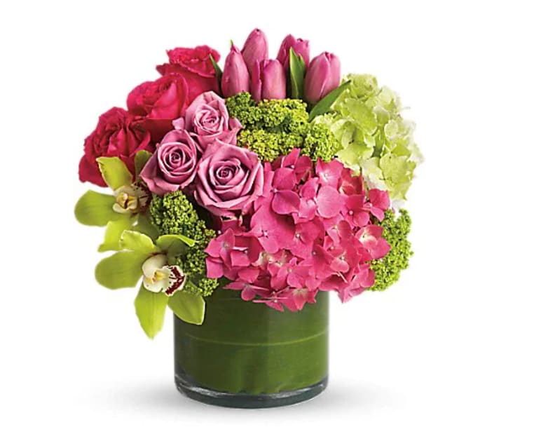 New Sensations - Upscale and uptown. This fantastic arrangement is a beauty and a half to behold. Overflowing with gorgeous blossoms and delivered in a leaf-lined cylinder vase, it's truly a floral fantasy. Green and pink hydrangeas, green cymbidium orchids, hot pink and lavender roses, tulips and more are beautifully arranged in a large clear glass cylinder vase. 