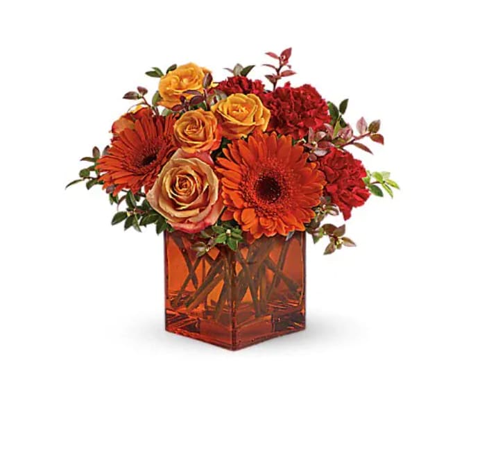 Sunrise Sunset - Sunrise, sunset, swiftly fly the days. So don't let another day go by without letting someone you know that you are thinking of them. This delightful arrangement will brighten anyone's morning, noon and night. Fiery orange roses, spray roses and gerberas plus red carnations and huckleberry, are arranged in an exclusive orange cube vase. This arrangement is bound to get glowing reviews and thank-yous! 