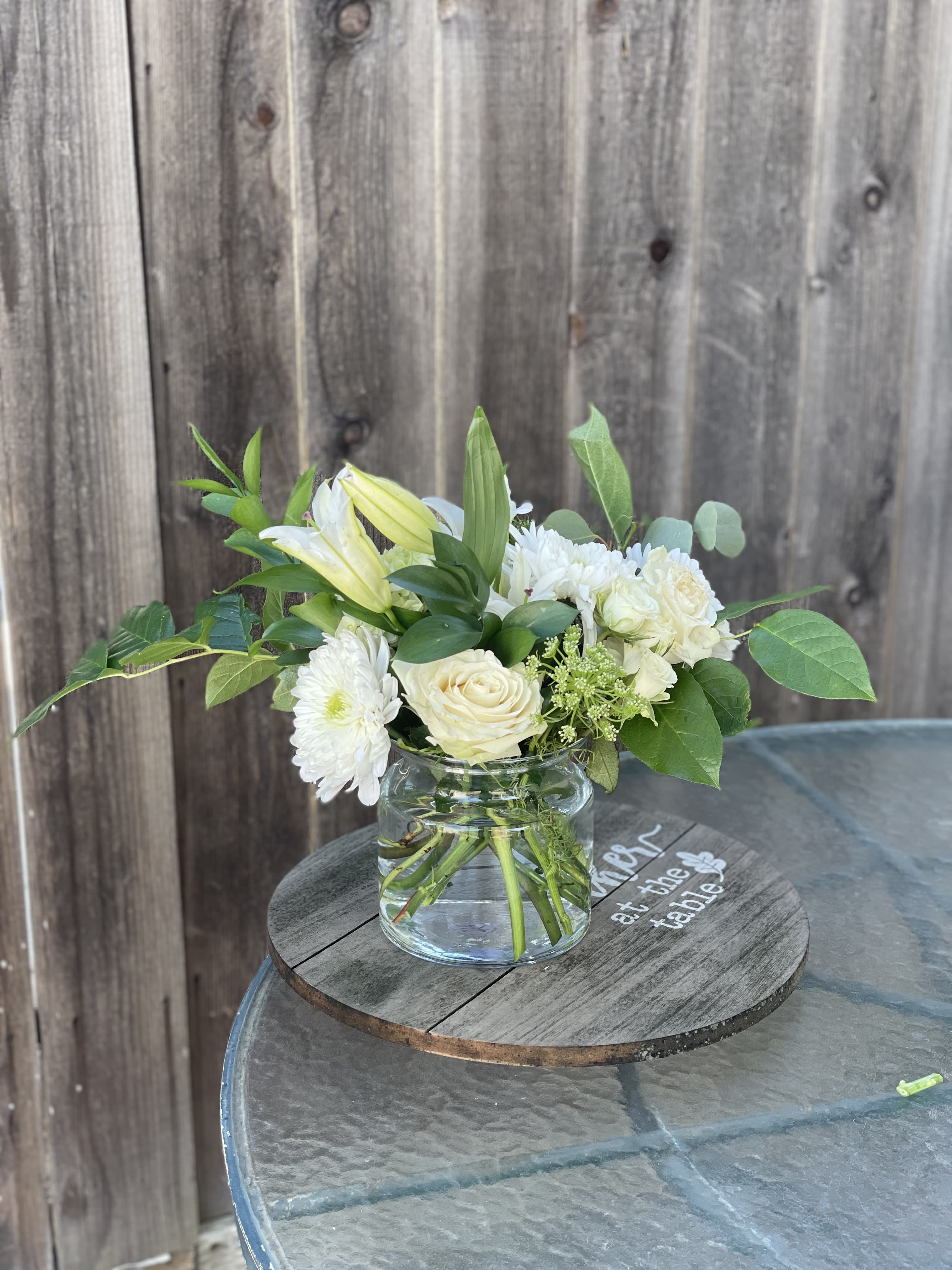 White flowers and pale yellow lilies in a clear glass vase