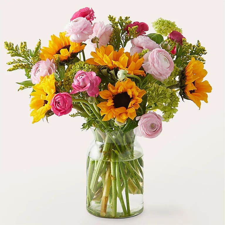 Bouquet of sunflowers and pink ranunculus in a clear glass vase
