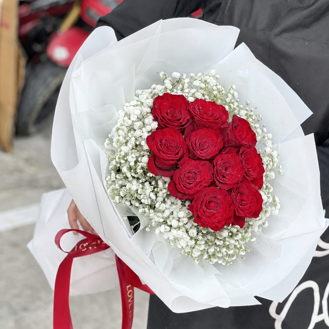 Bouquet of red roses with white baby's breath wrapped in white paper