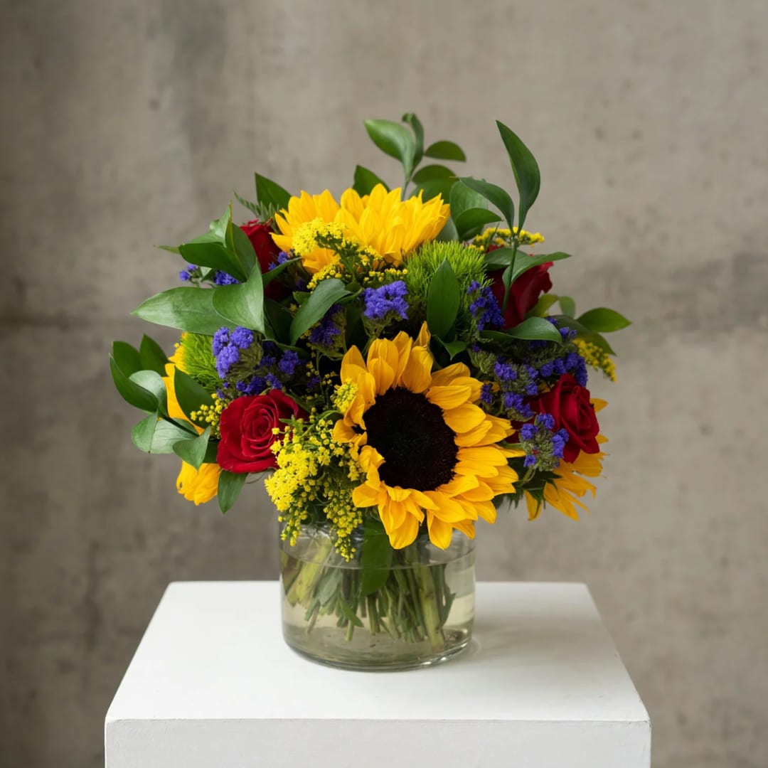 Bouquet of sunflowers and red roses in a clear glass vase