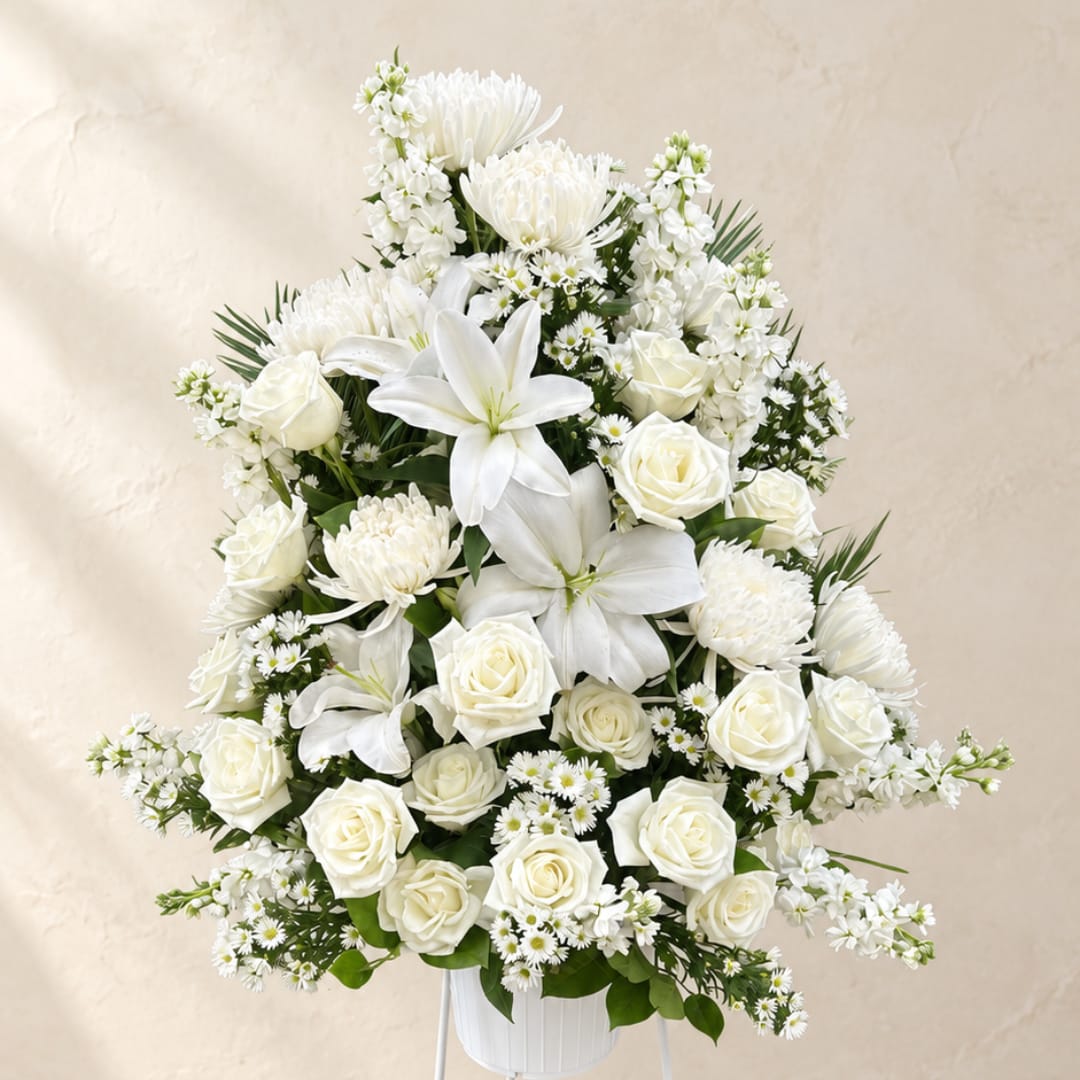 White floral arrangement with roses, lilies, and daisies in a white vase