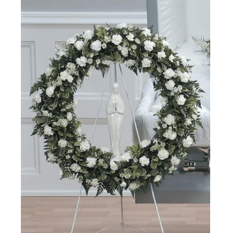 Large white floral wreath on a stand with a central figurine