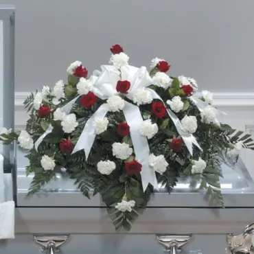 Red and white floral casket spray with a white bow