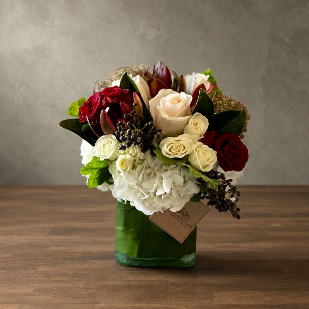 Bouquet of red and white roses in a green glass vase