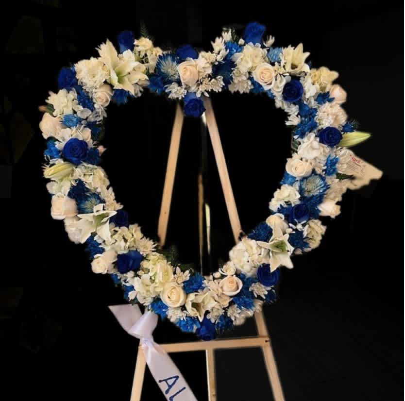 Heart-shaped floral wreath with blue and white flowers on an easel