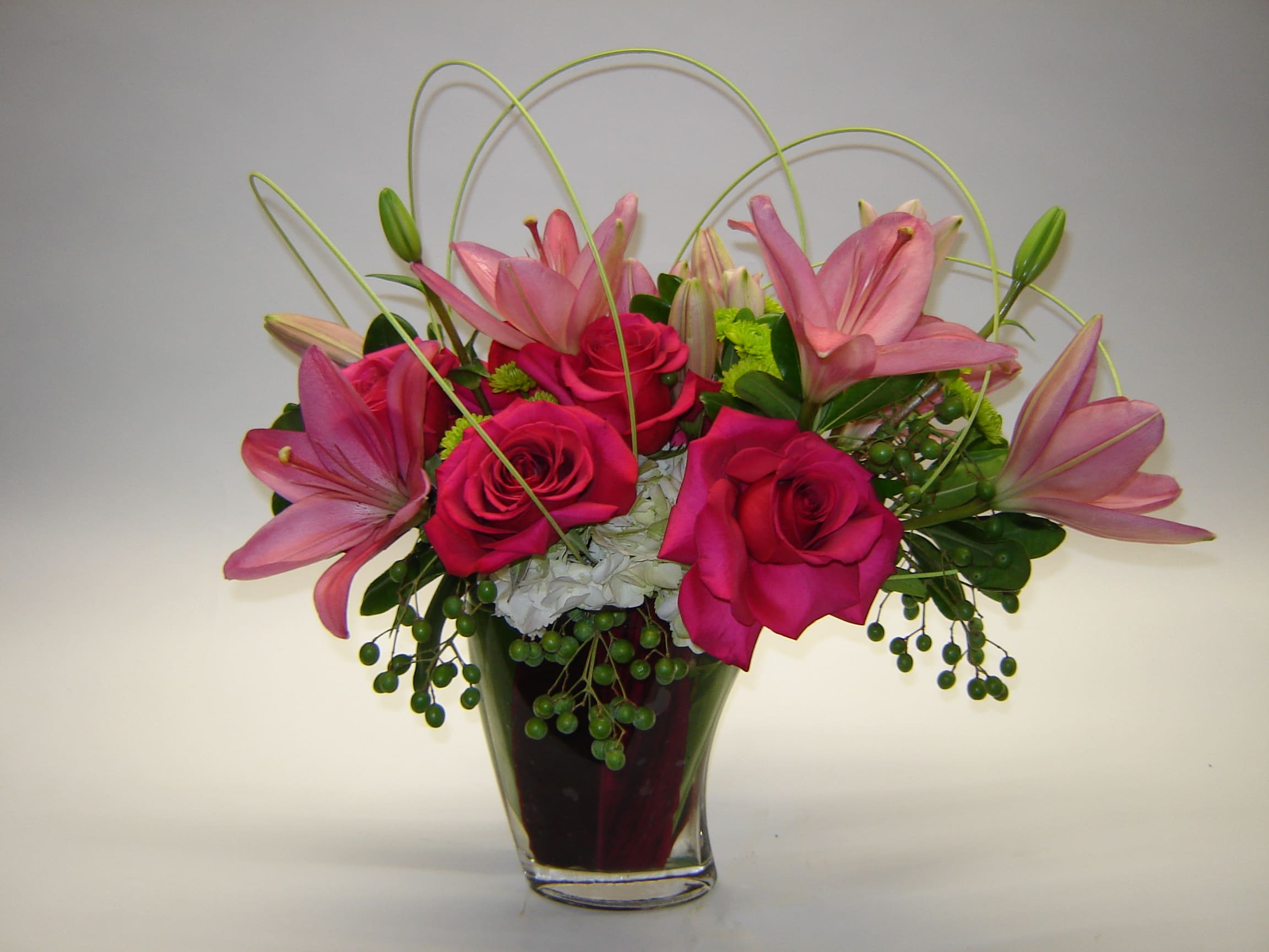 Pink roses and lilies in a clear glass vase