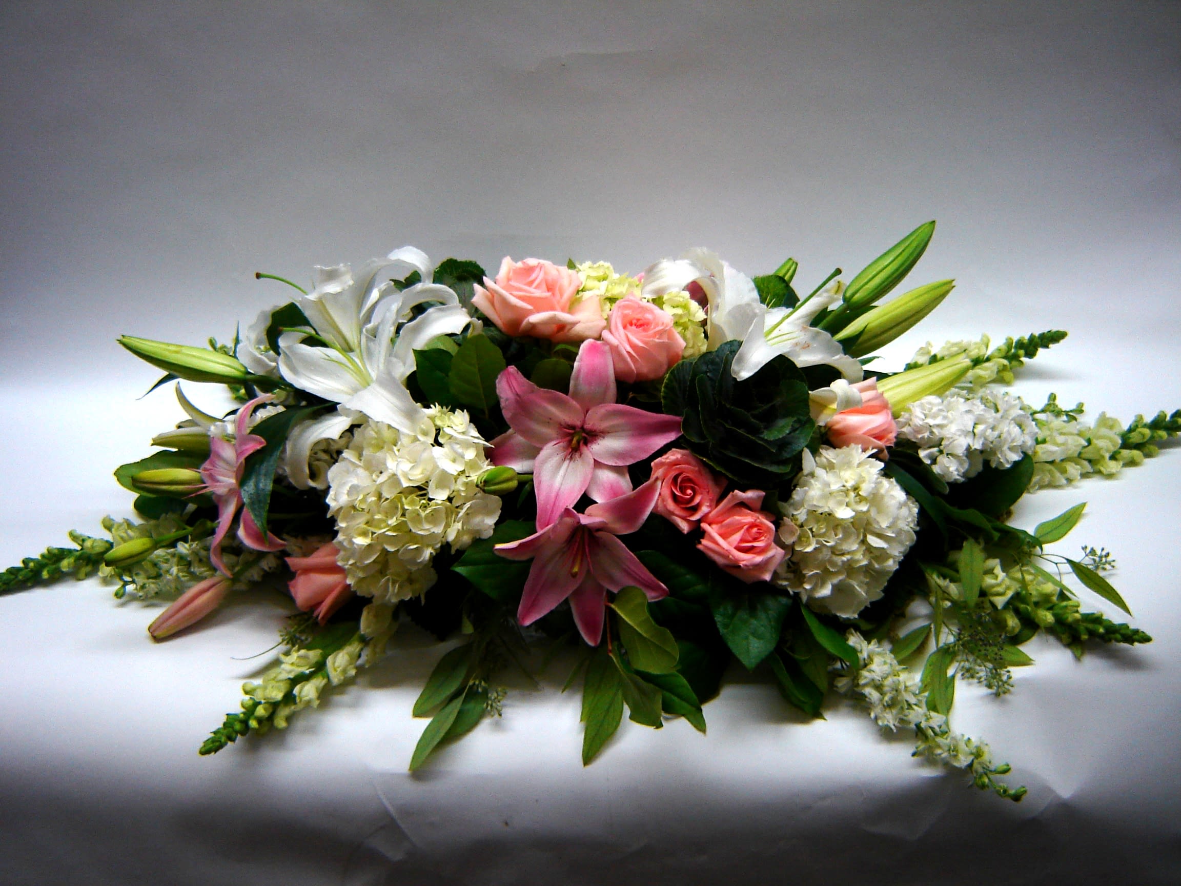 Low floral centerpiece with pink roses, white lilies, and hydrangeas