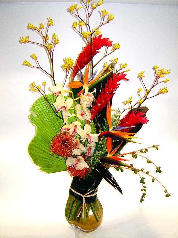 Tropical flower arrangement in a glass vase with red and orange blooms