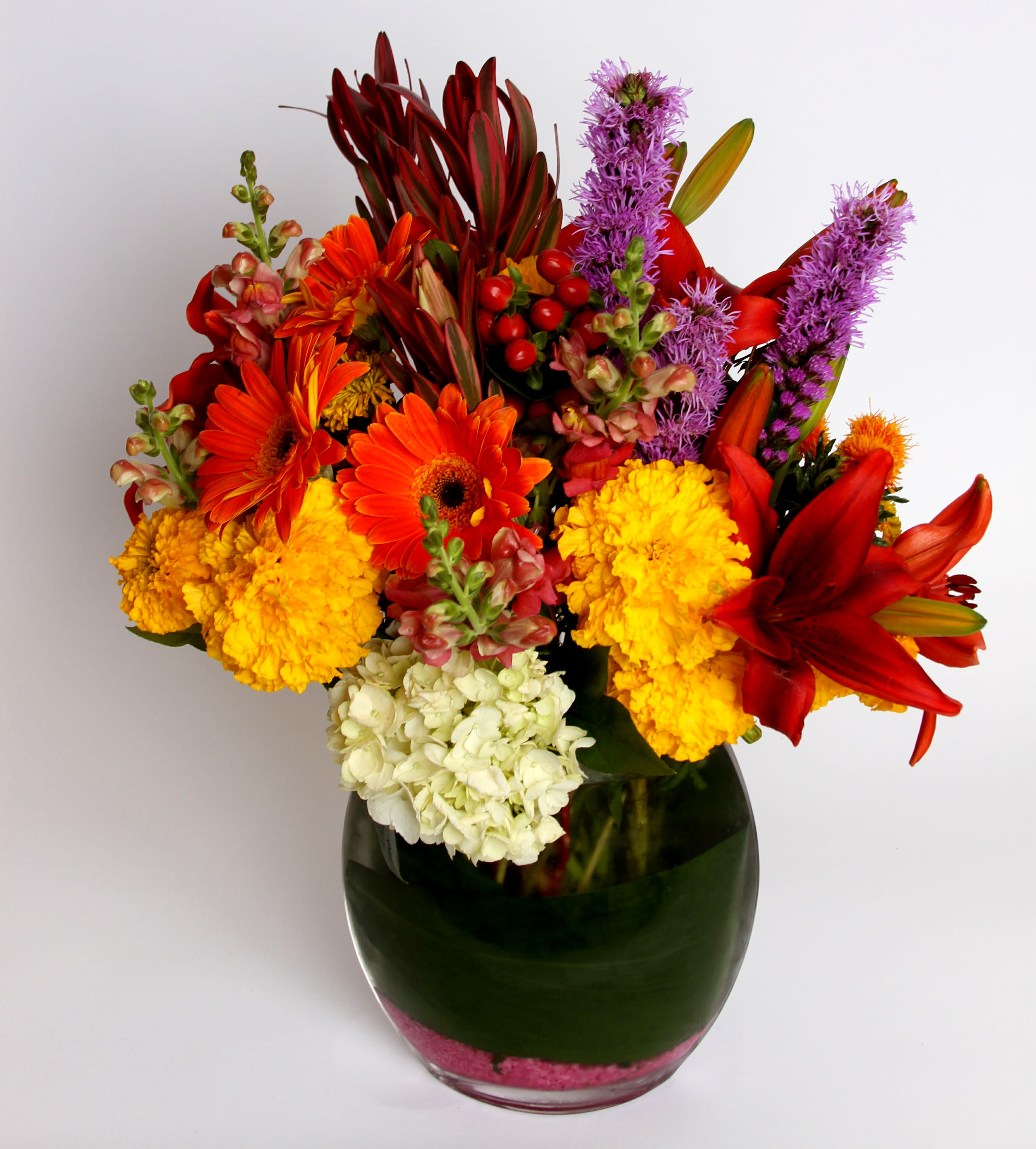 Bright mixed bouquet in a glass vase with red, orange, yellow, purple, and white blooms