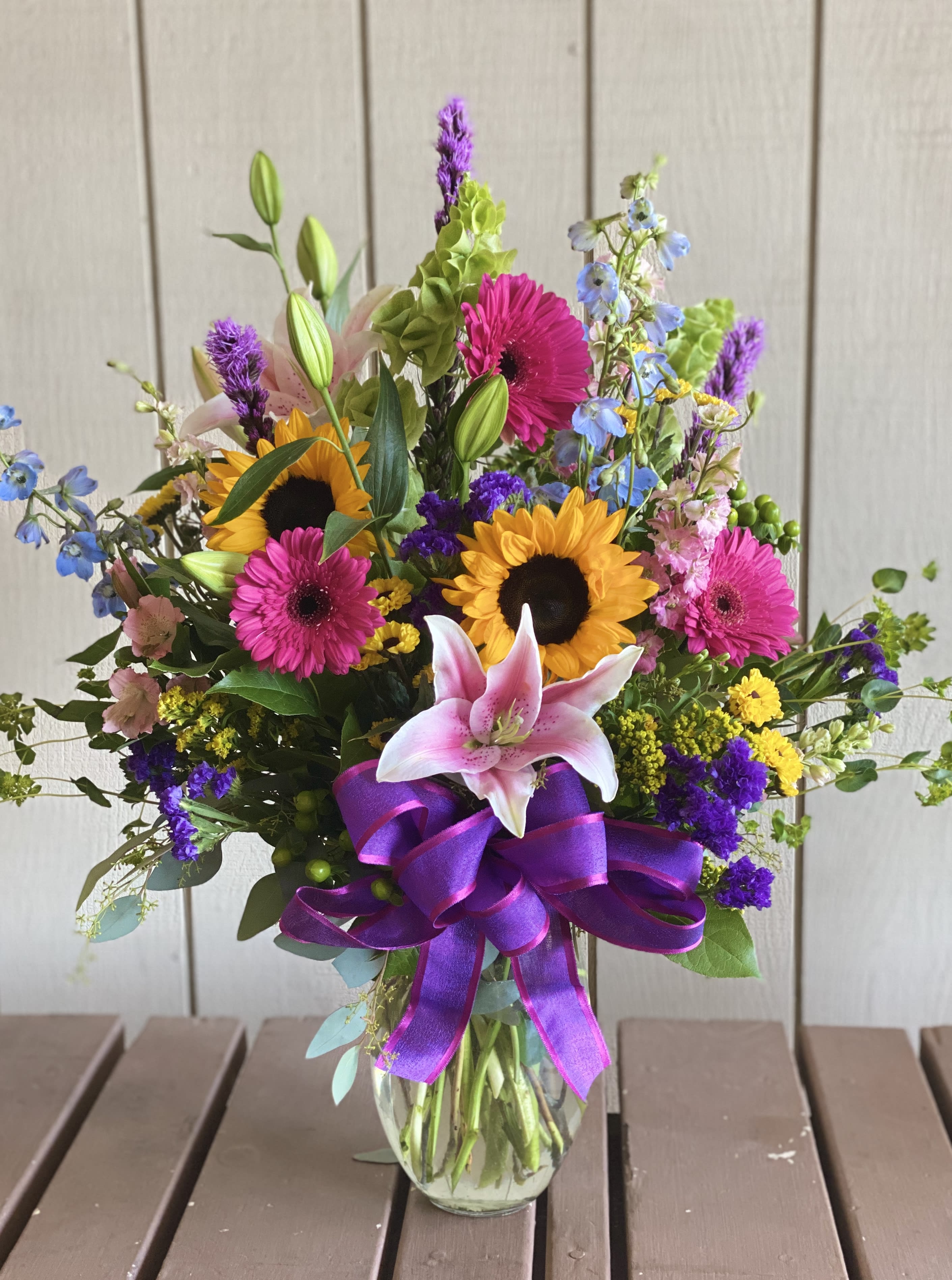 Colorful mixed bouquet in a glass vase with a purple ribbon