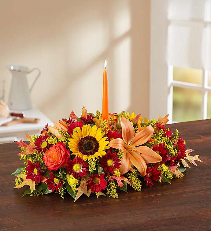 Autumn floral centerpiece with a lit orange taper candle