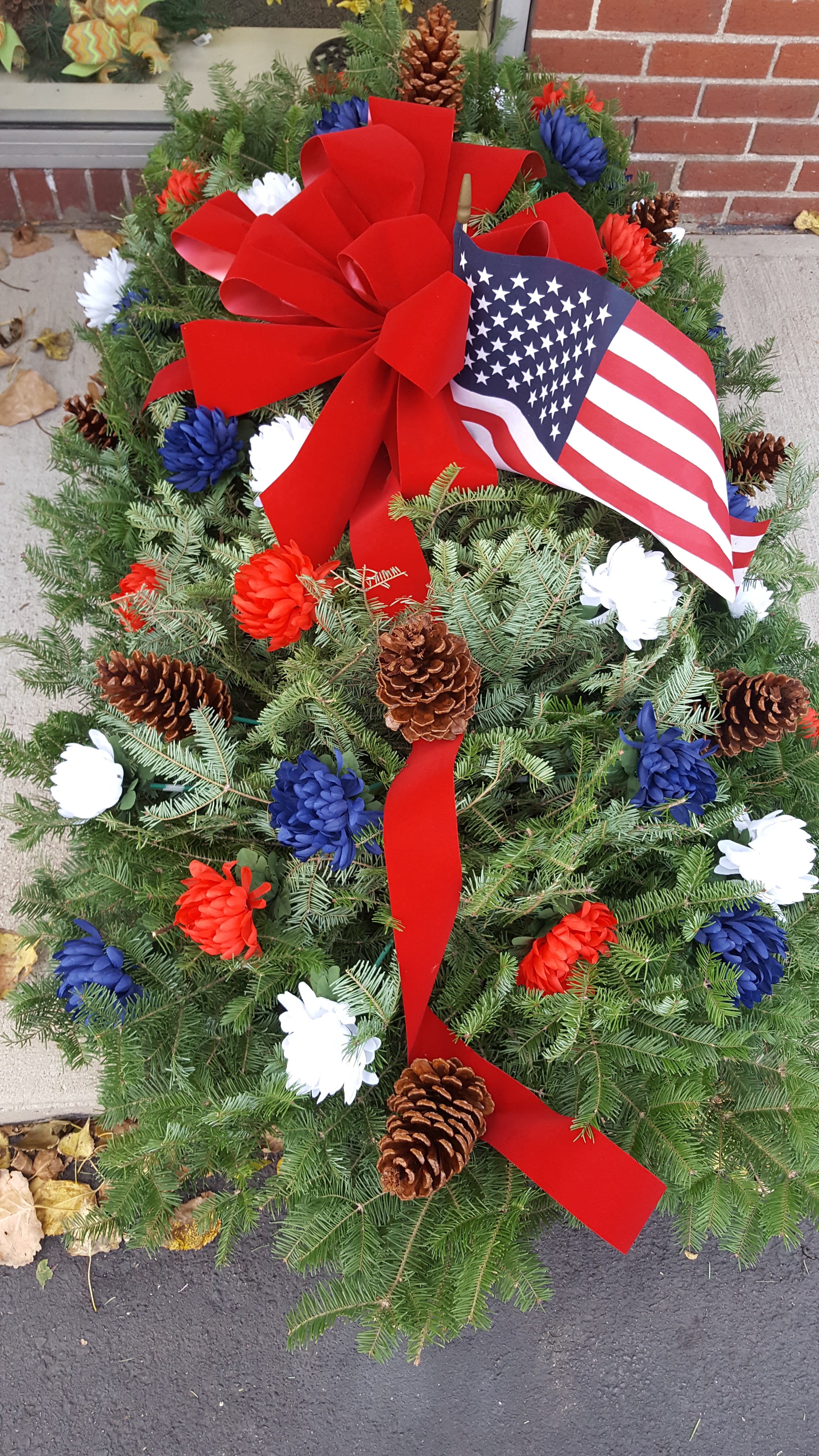 Patriotic wreath with red bow, American flag, and red white blue flowers