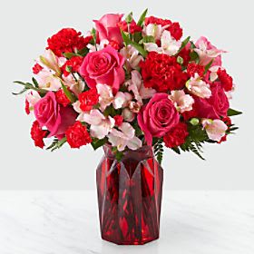 Pink and red mixed flower bouquet in a red glass vase