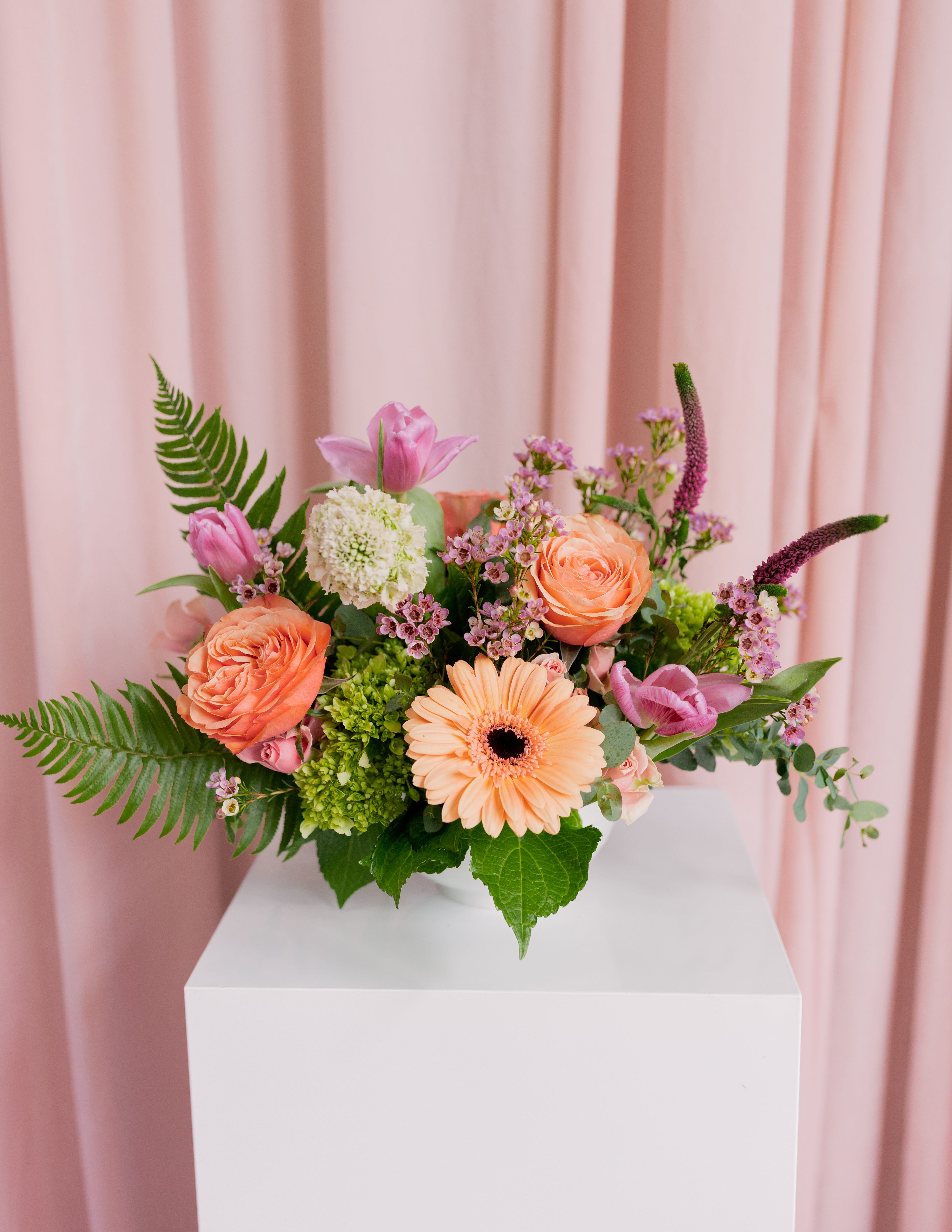 Pink and peach floral arrangement in a white vase