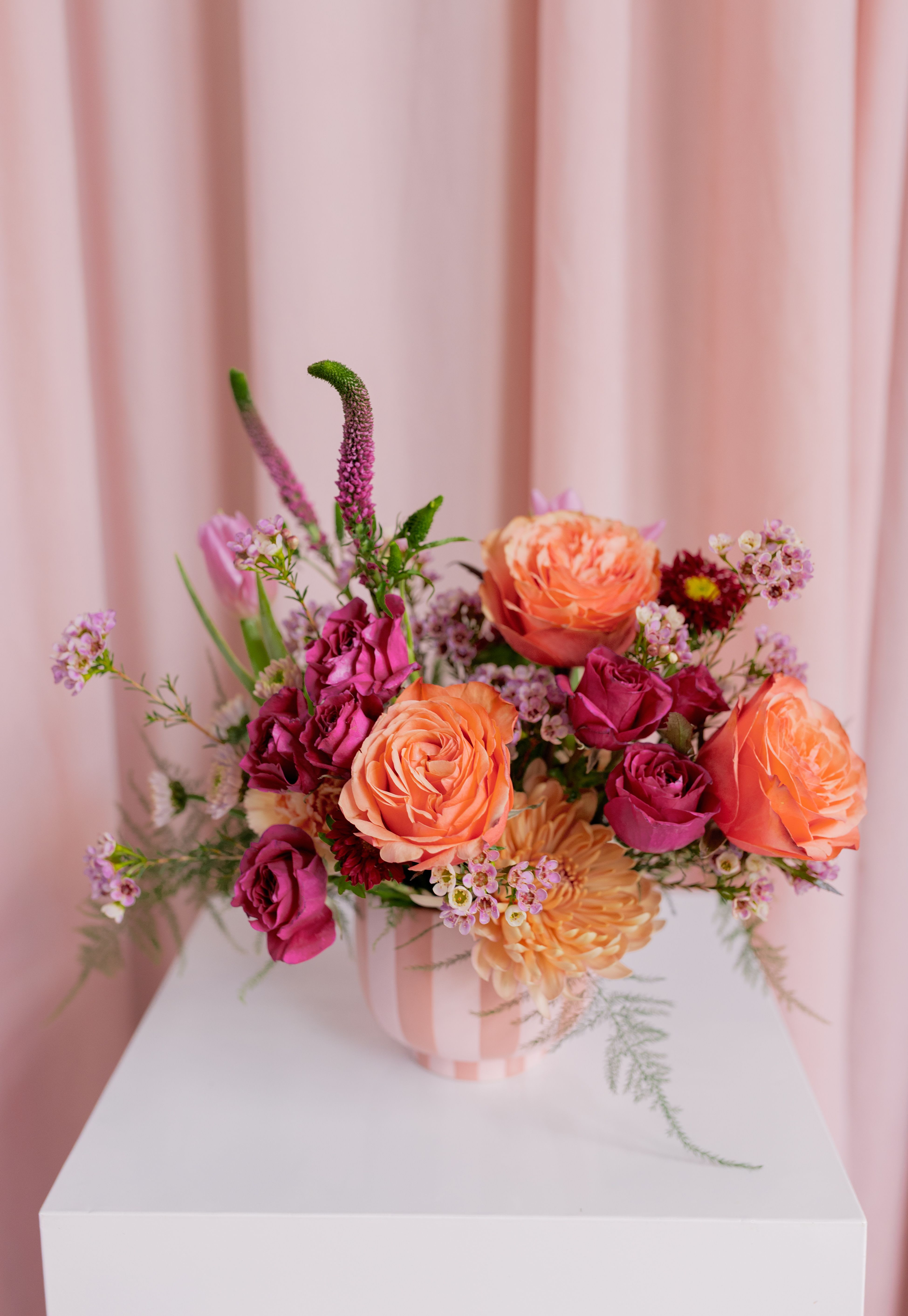 Pink and peach rose bouquet in a striped vase