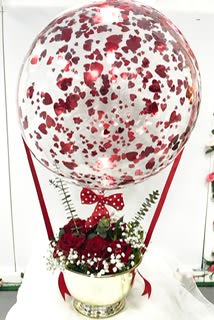 Heart-patterned balloon above a red rose arrangement in a gold vase