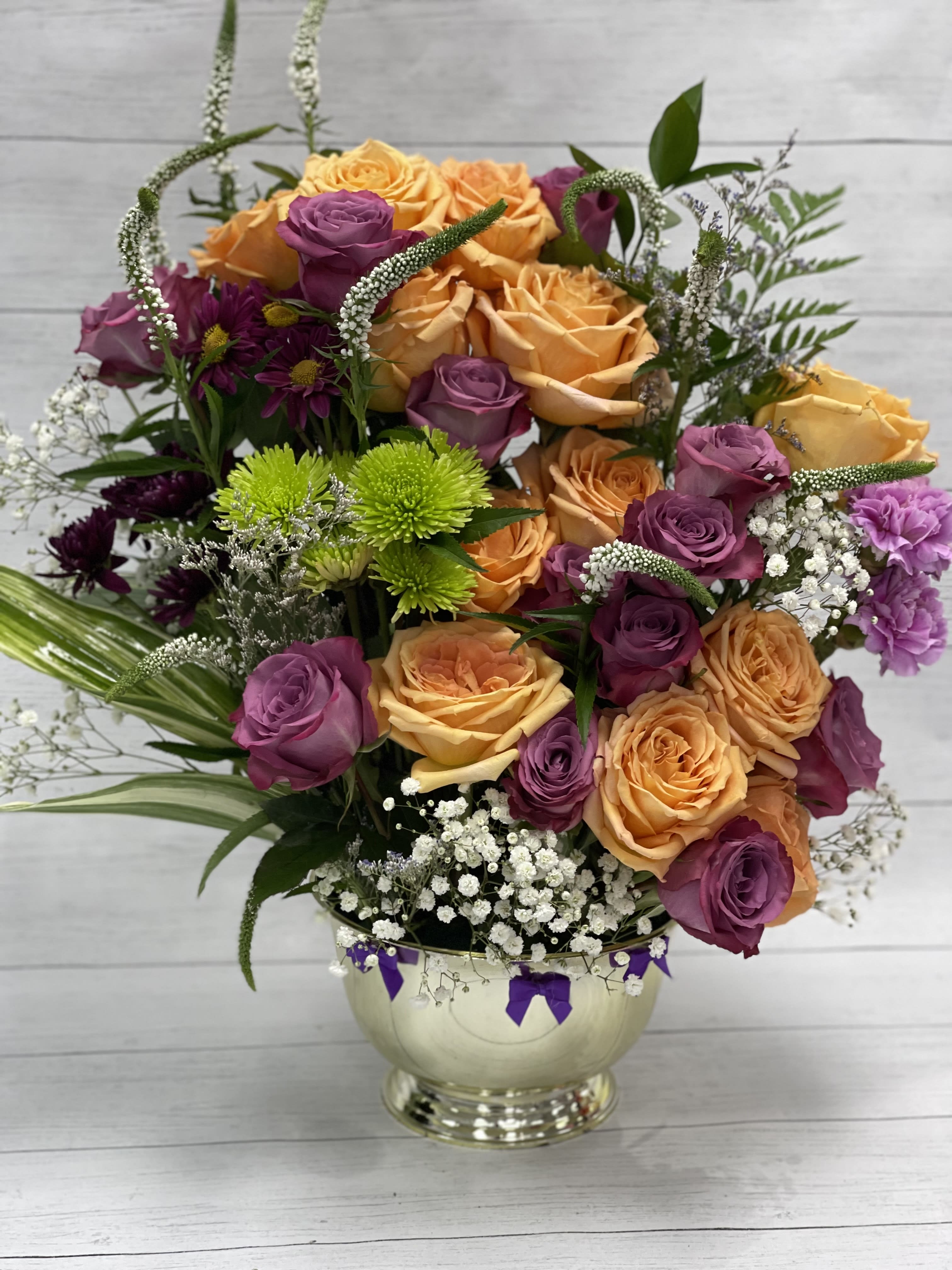 Bouquet of orange and purple roses in a gold vase