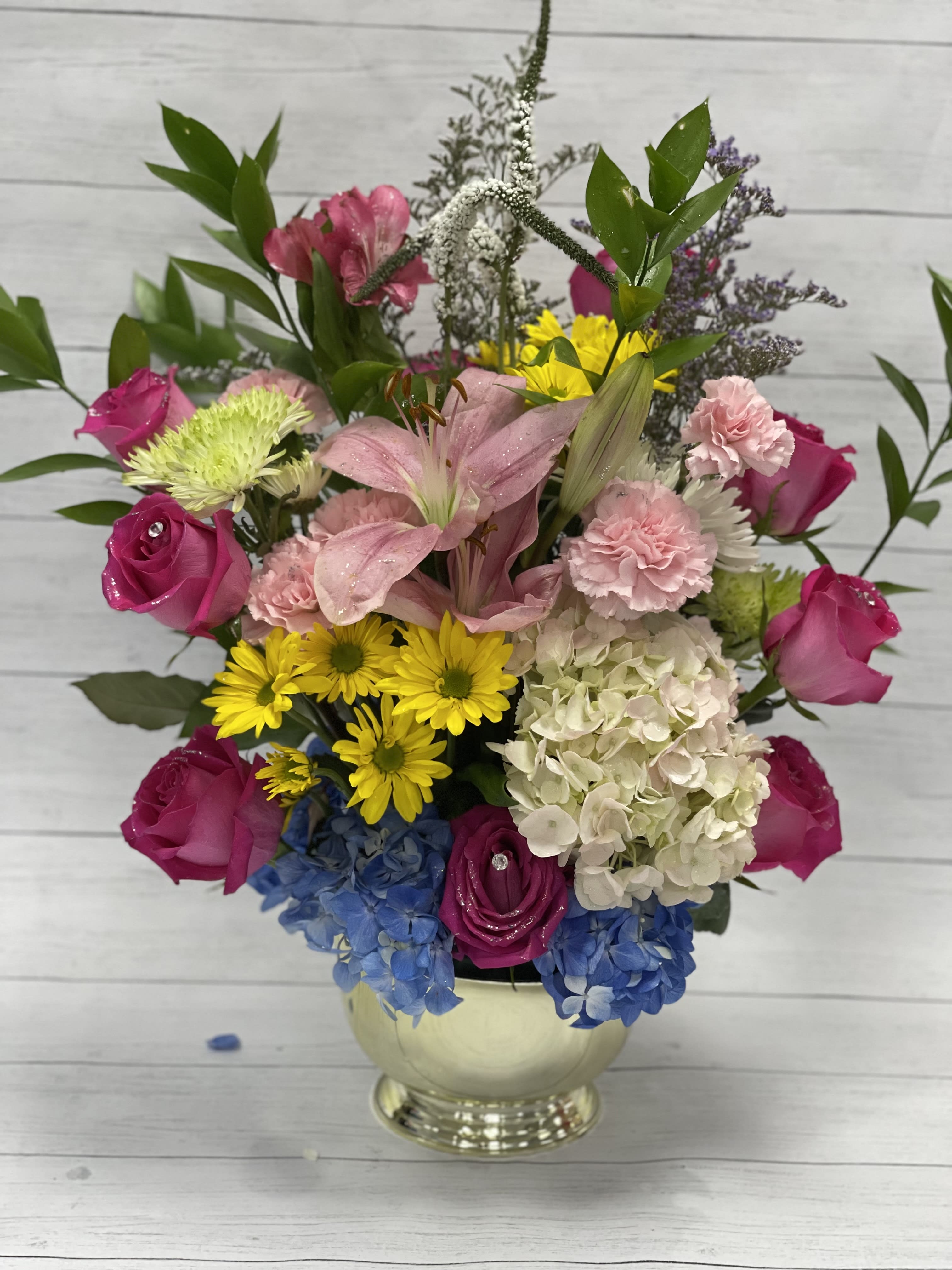 Mixed bouquet with pink roses, lilies, hydrangea, and yellow daisies in a vase