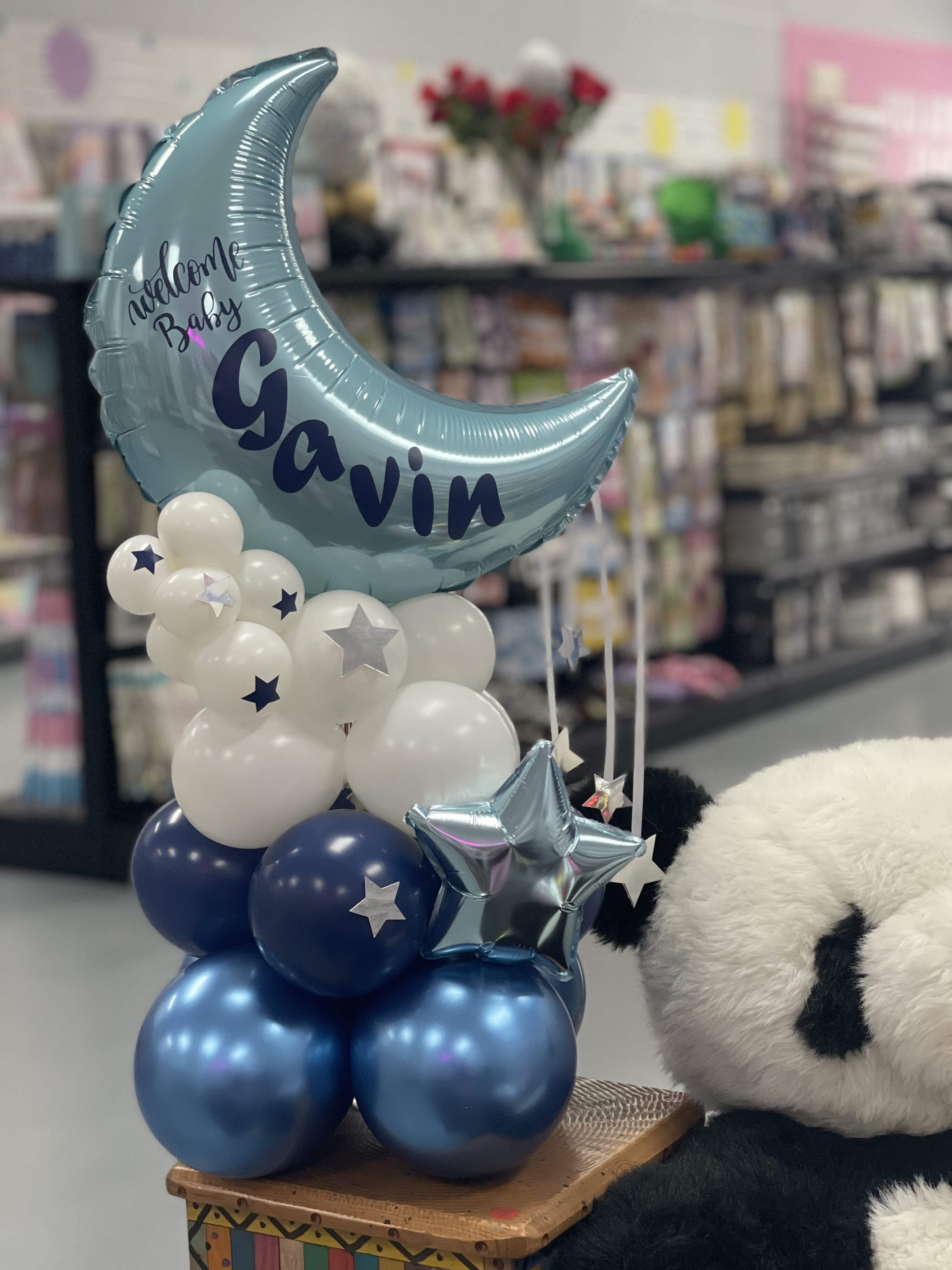 Blue moon balloon with white and navy balloons and a teddy bear