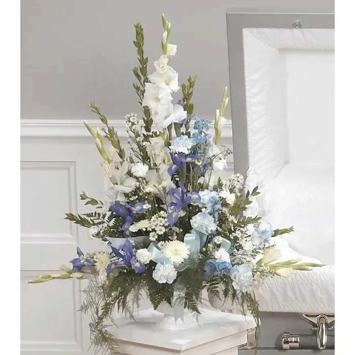 Tall white and blue floral spray in a white stand