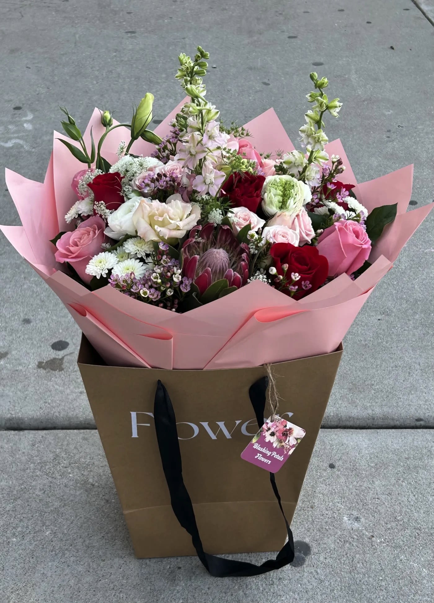 Mixed bouquet of pink, red, and white flowers in pink wrap
