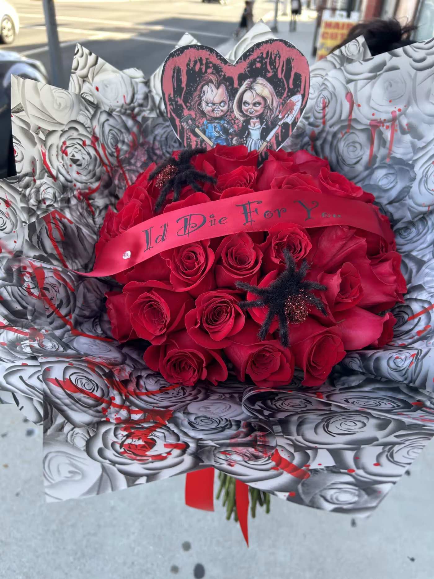 Red rose bouquet with a horror-themed heart topper and ribbon