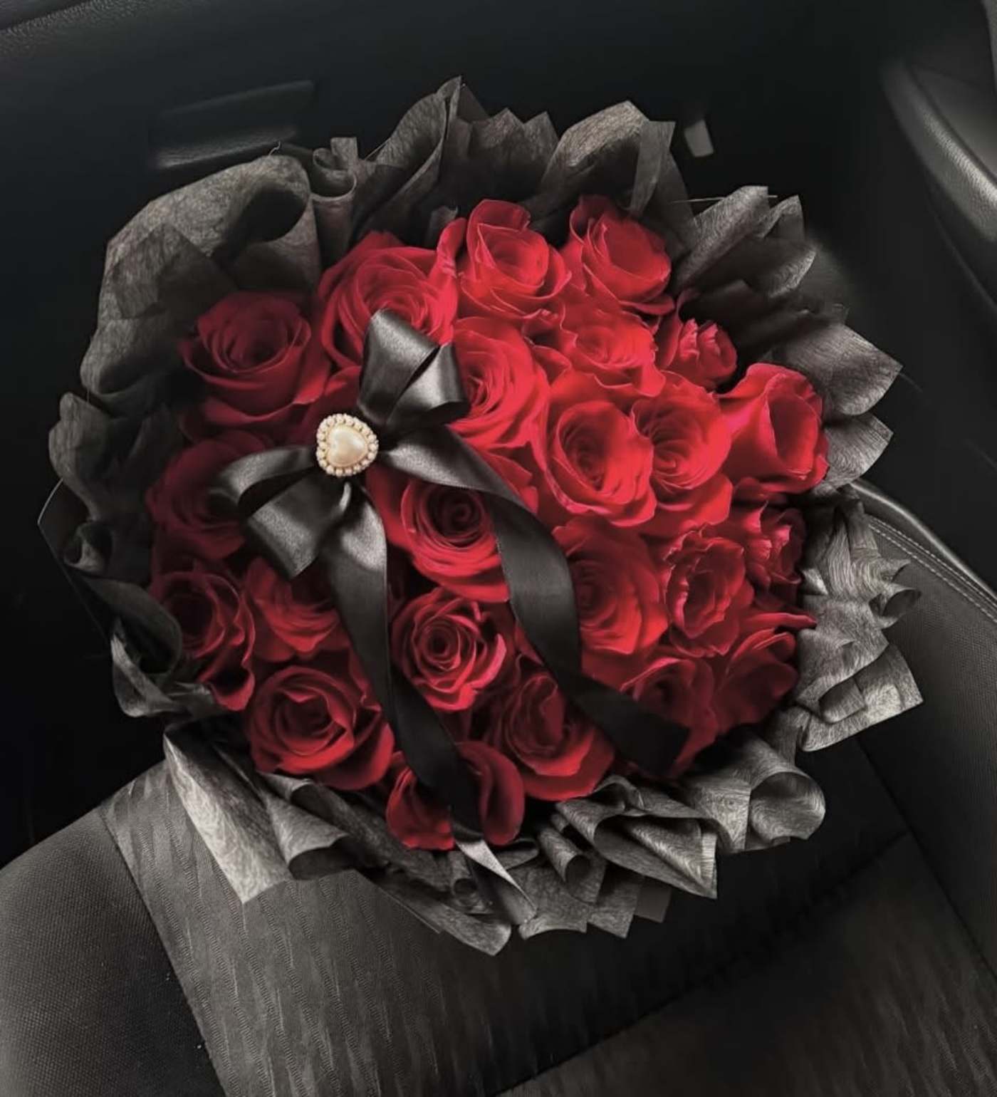 Bouquet of red roses wrapped in black paper with a black ribbon