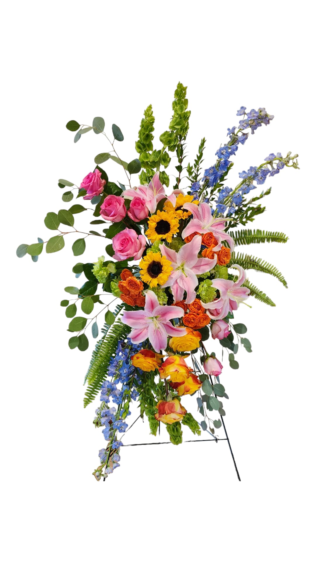 Tall standing floral spray with pink lilies, roses, sunflowers, and blue delphinium