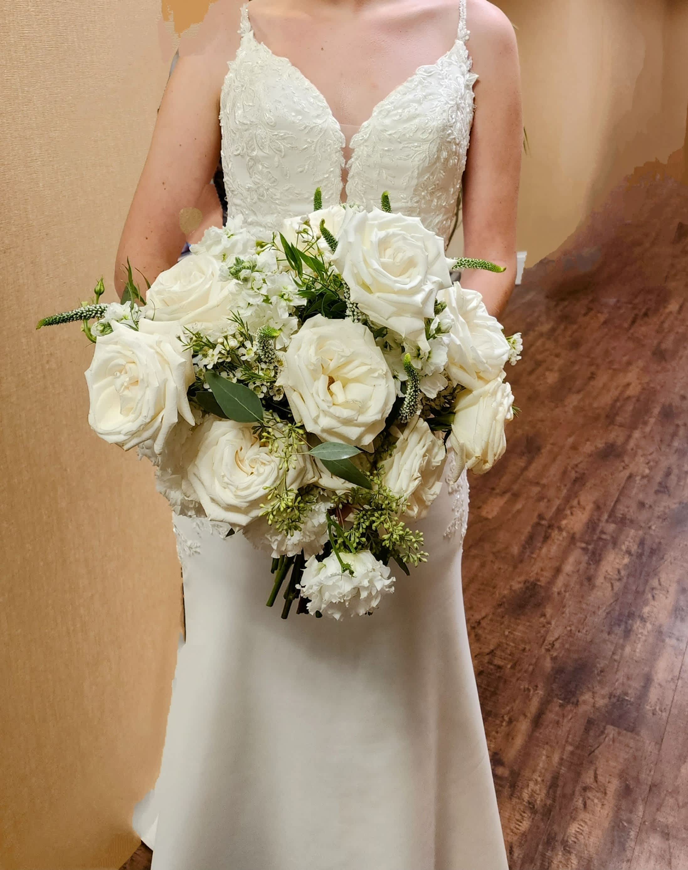 Bride holding a bouquet of white roses and greenery