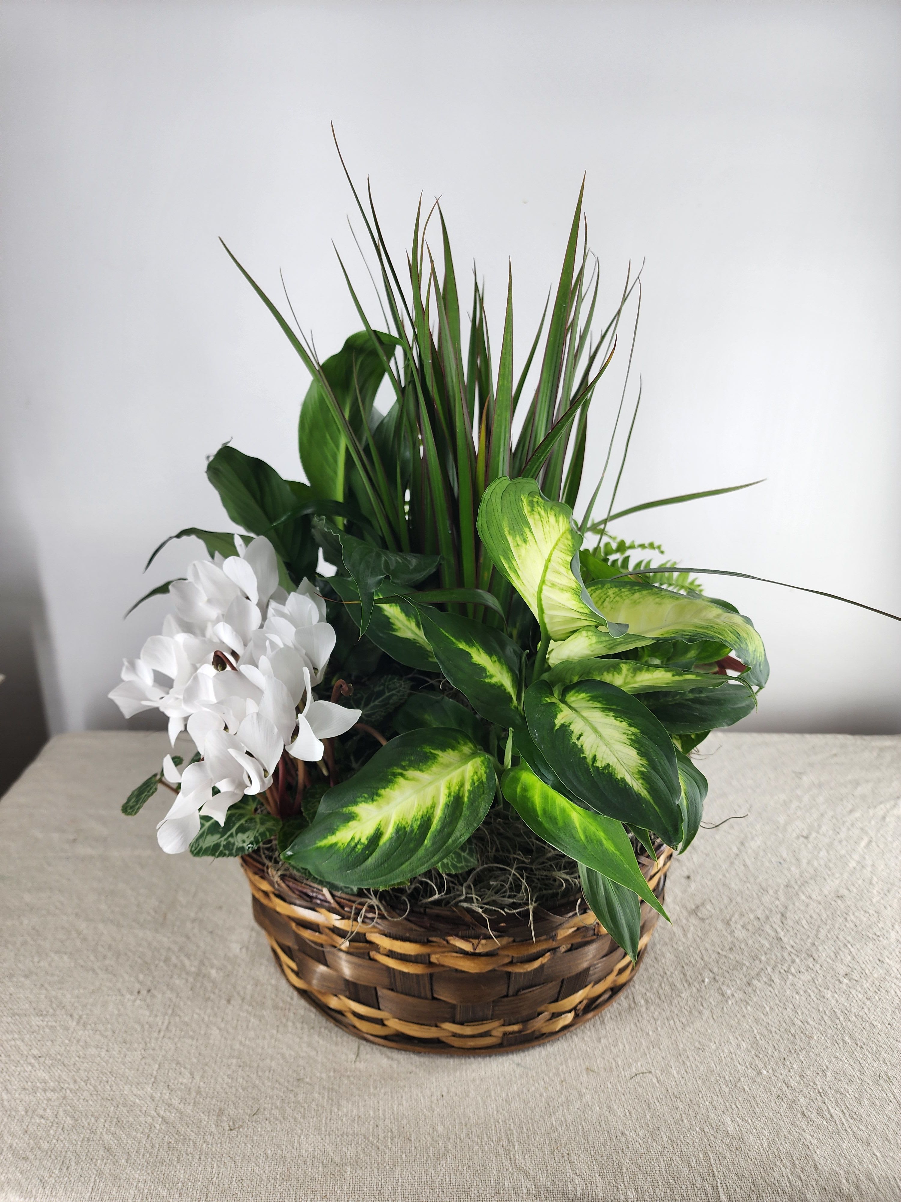 White flowers and green foliage arranged in a wicker basket