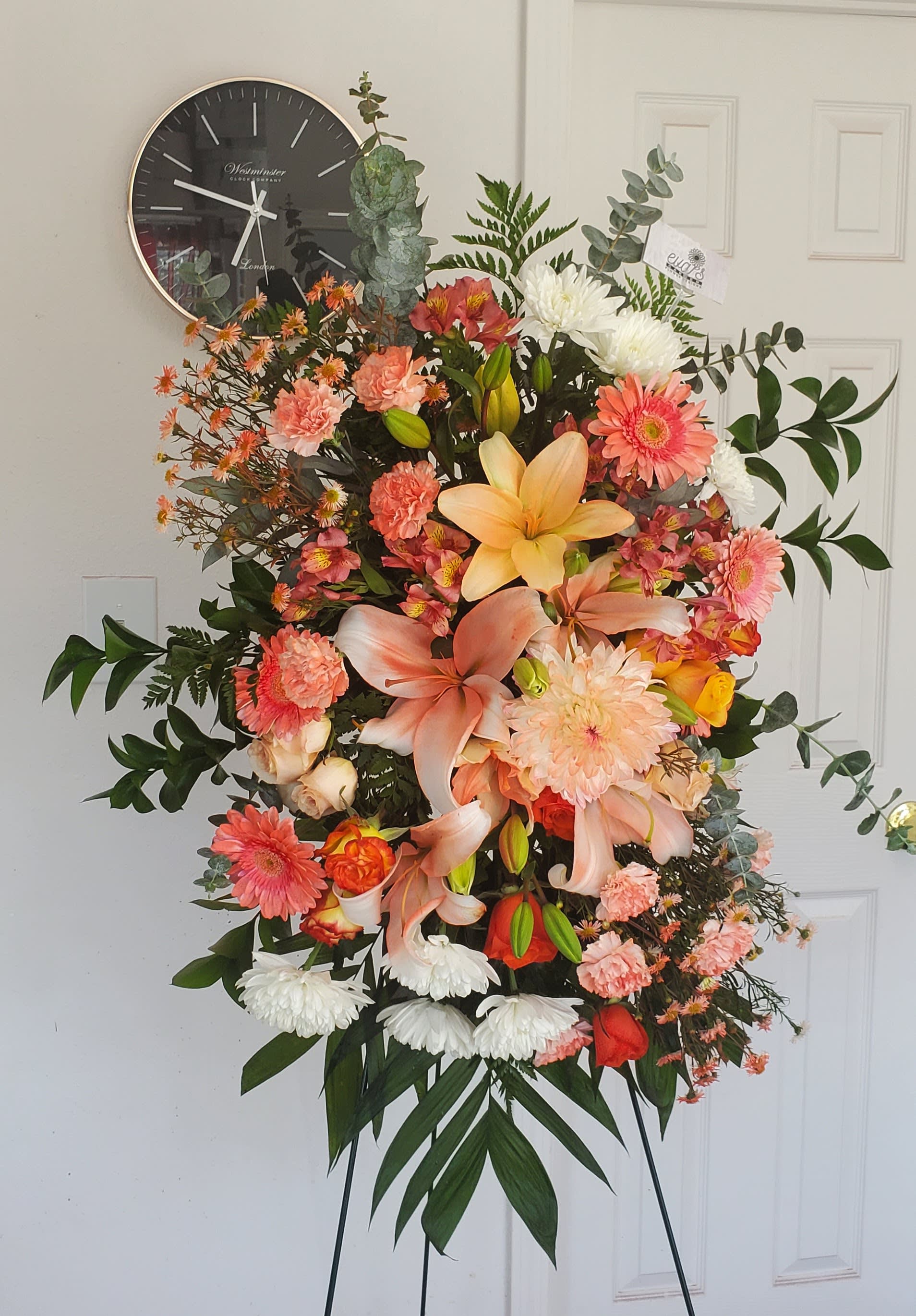 Orange and Peach Funeral Spray - Light orange funeral spray with gerber daisies, mums, carnations, roses, montecasino, alstroemeria, and lilies.   (Picture depicts a deluxe product; standard &amp; premium size available upon request)
