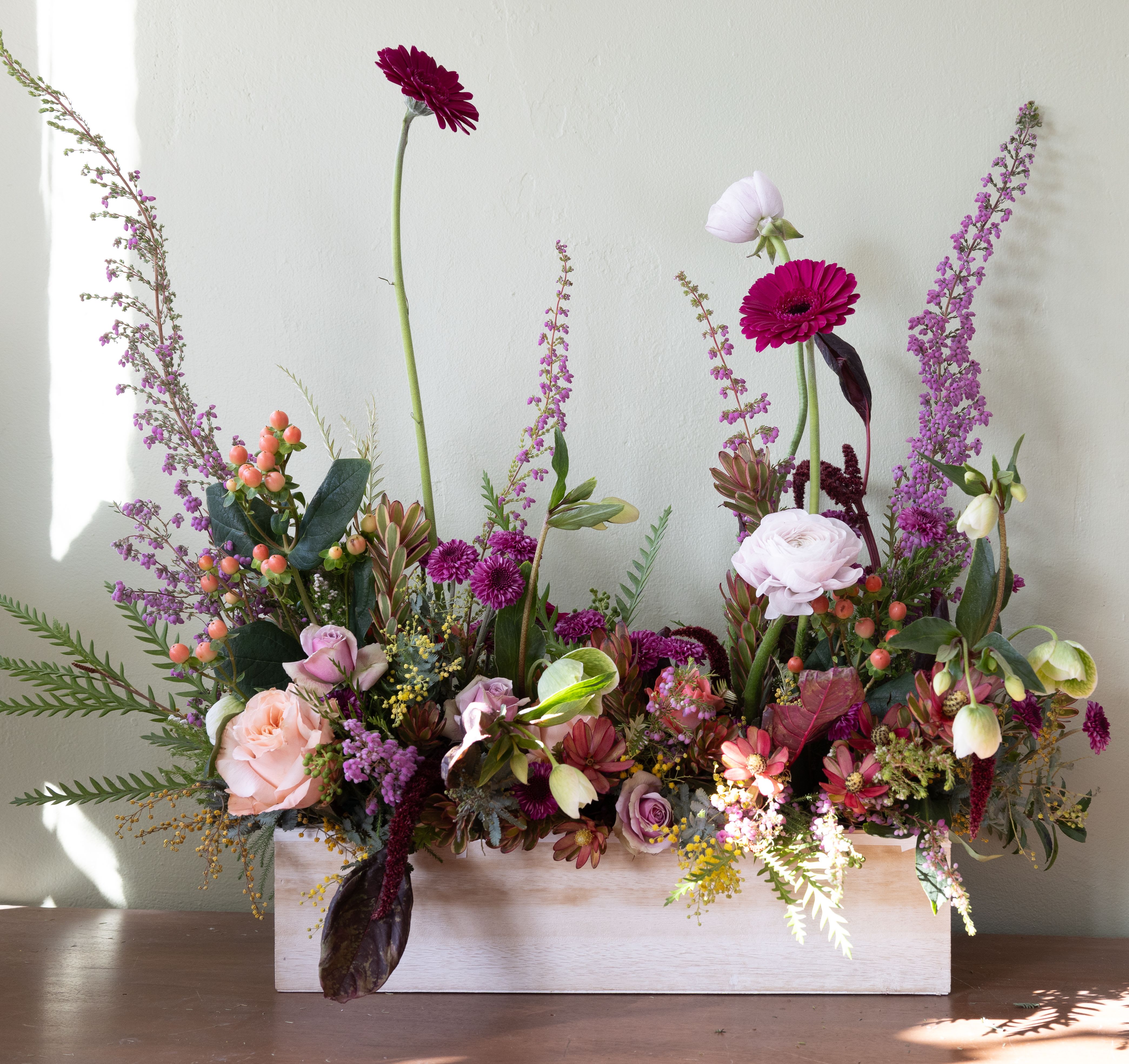 Mixed floral arrangement in a white rectangular box with pink and purple blooms
