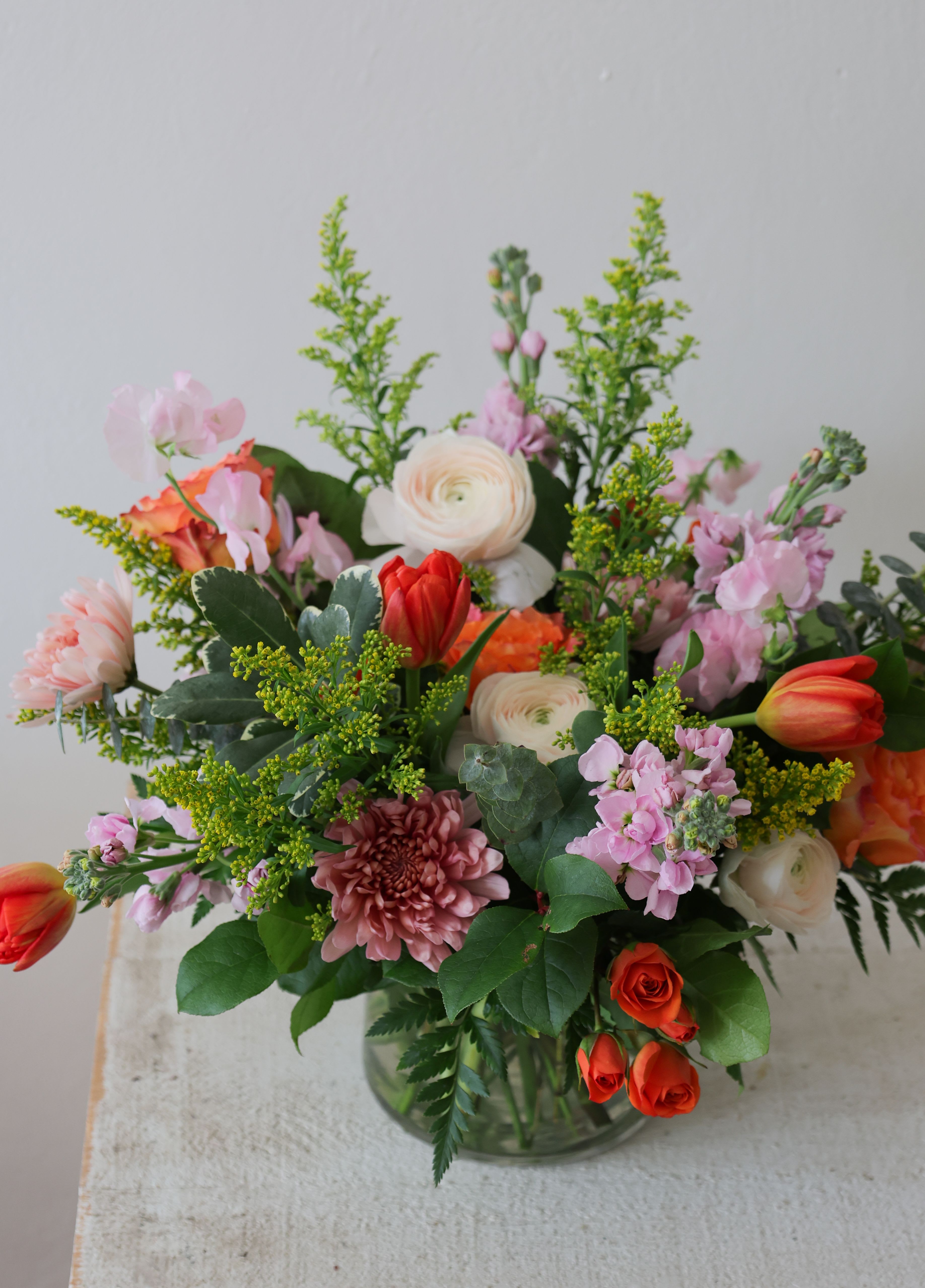 Mixed bouquet of pink, white, and orange flowers in a glass vase