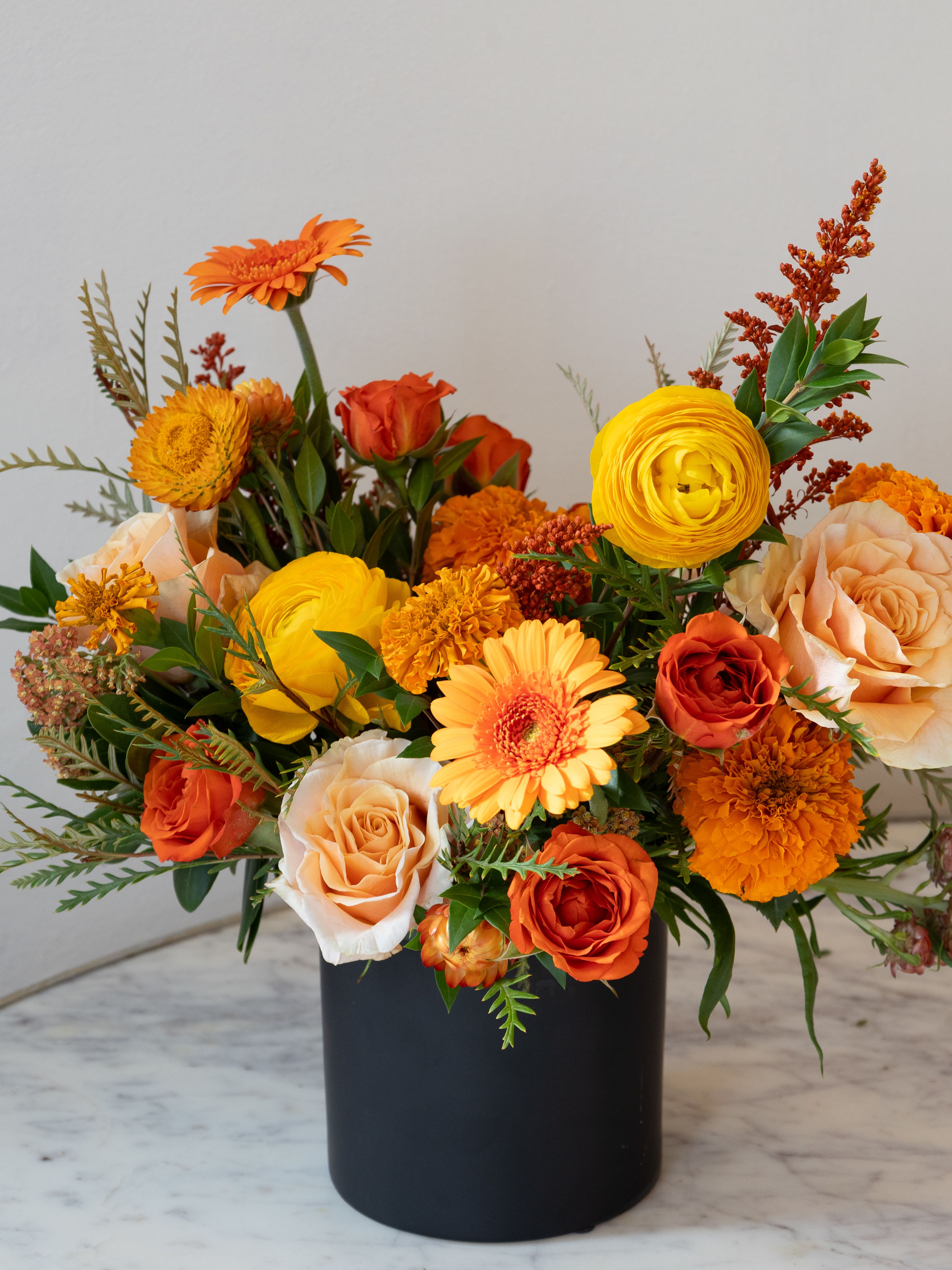 Orange and yellow mixed bouquet in a black vase