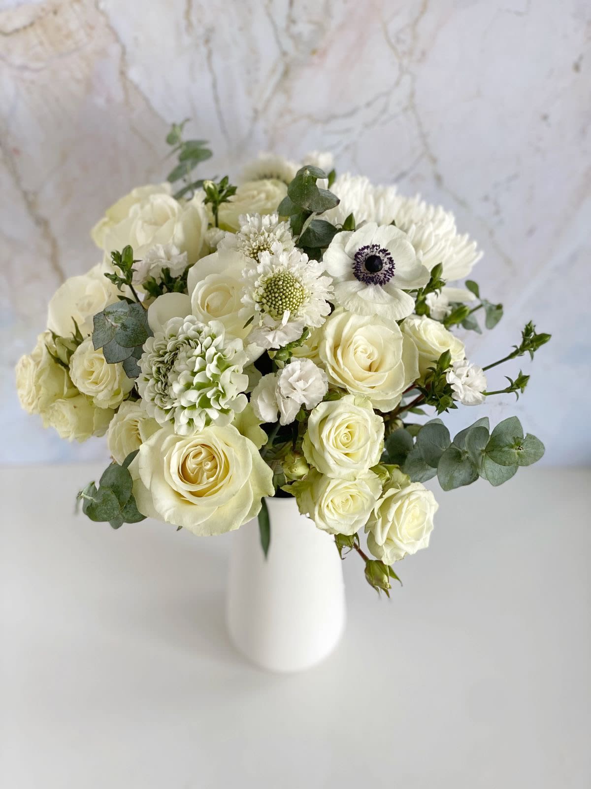 White rose bouquet in a white vase with eucalyptus