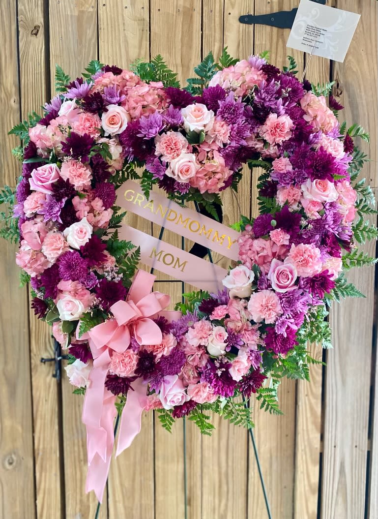 Heart-shaped floral wreath with pink and purple flowers and a ribbon