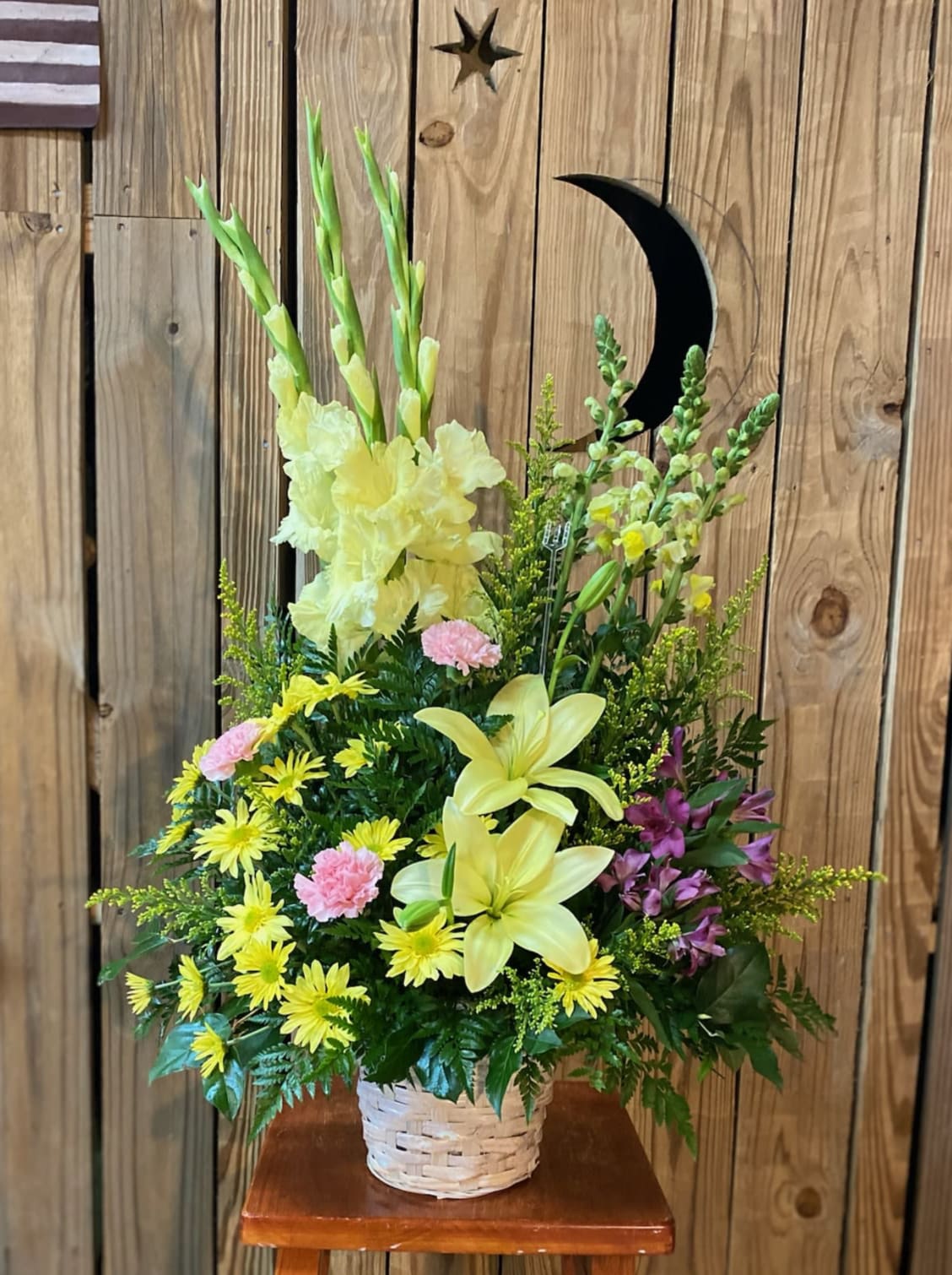 Vivid Recollections - Send sunshine to show you care. A symbol of friendship, these yellow sympathy flowers are accented with pretty pink carnations for a classic sympathy basket that will warm anyone's heart. This sunny arrangement includes flowers such as yellow asiatic lilies, yellow gladioli, yellow snapdragons, pink carnations, yellow daisies and greens such as oregonia, salal and leatherleaf fern. Delivered in a round basket.