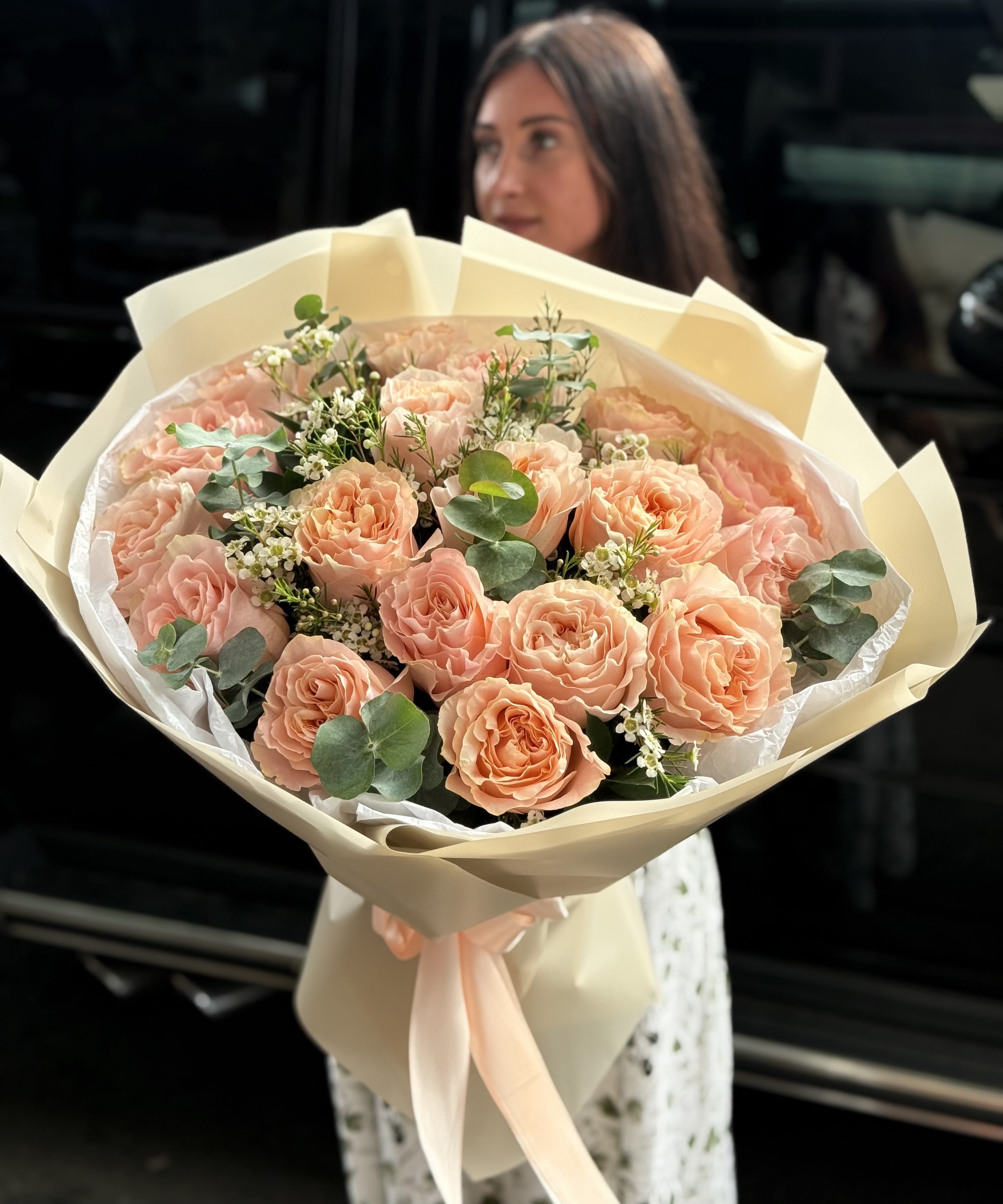 Peach rose bouquet wrapped in cream paper with a satin ribbon