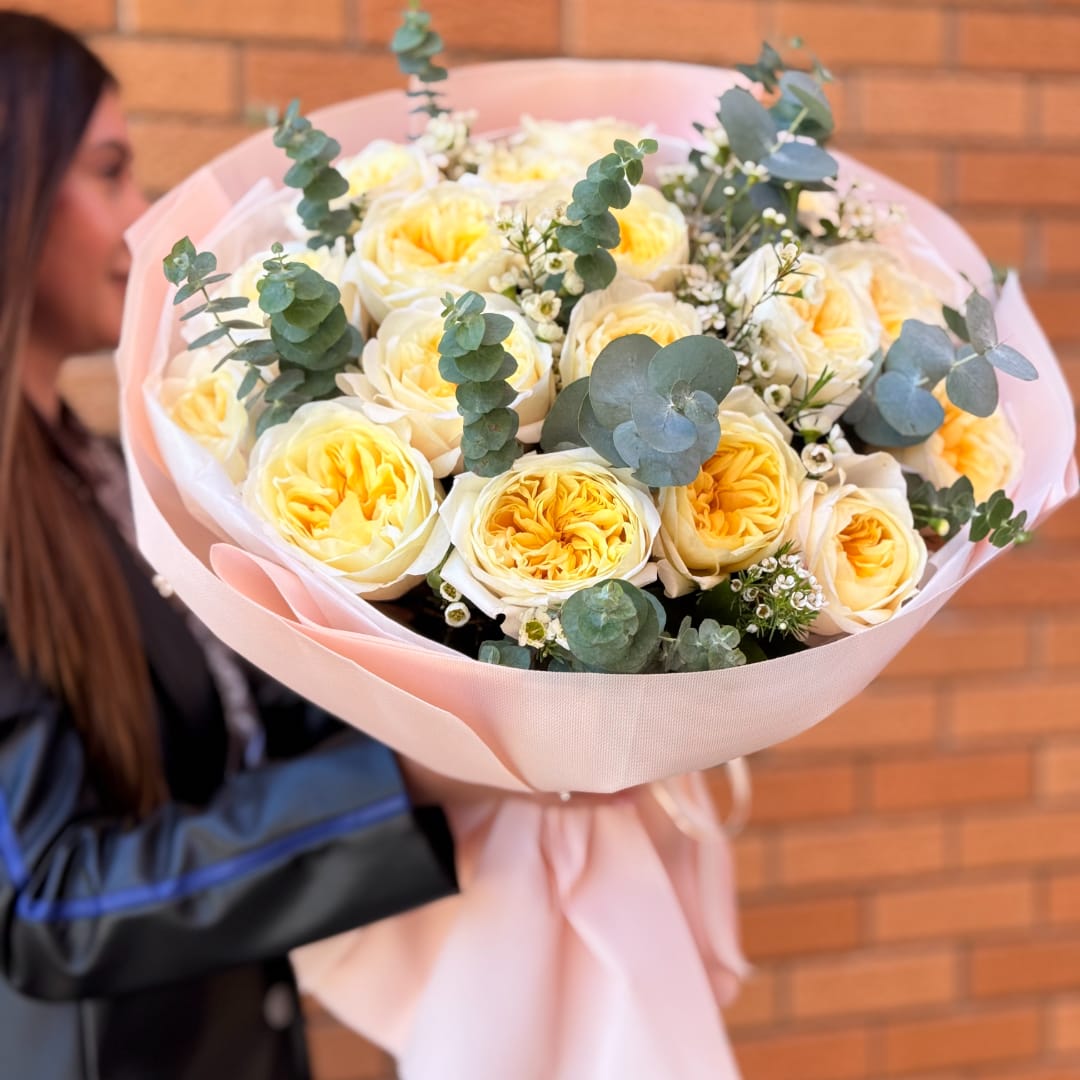Bouquet of pale yellow roses wrapped in pink paper