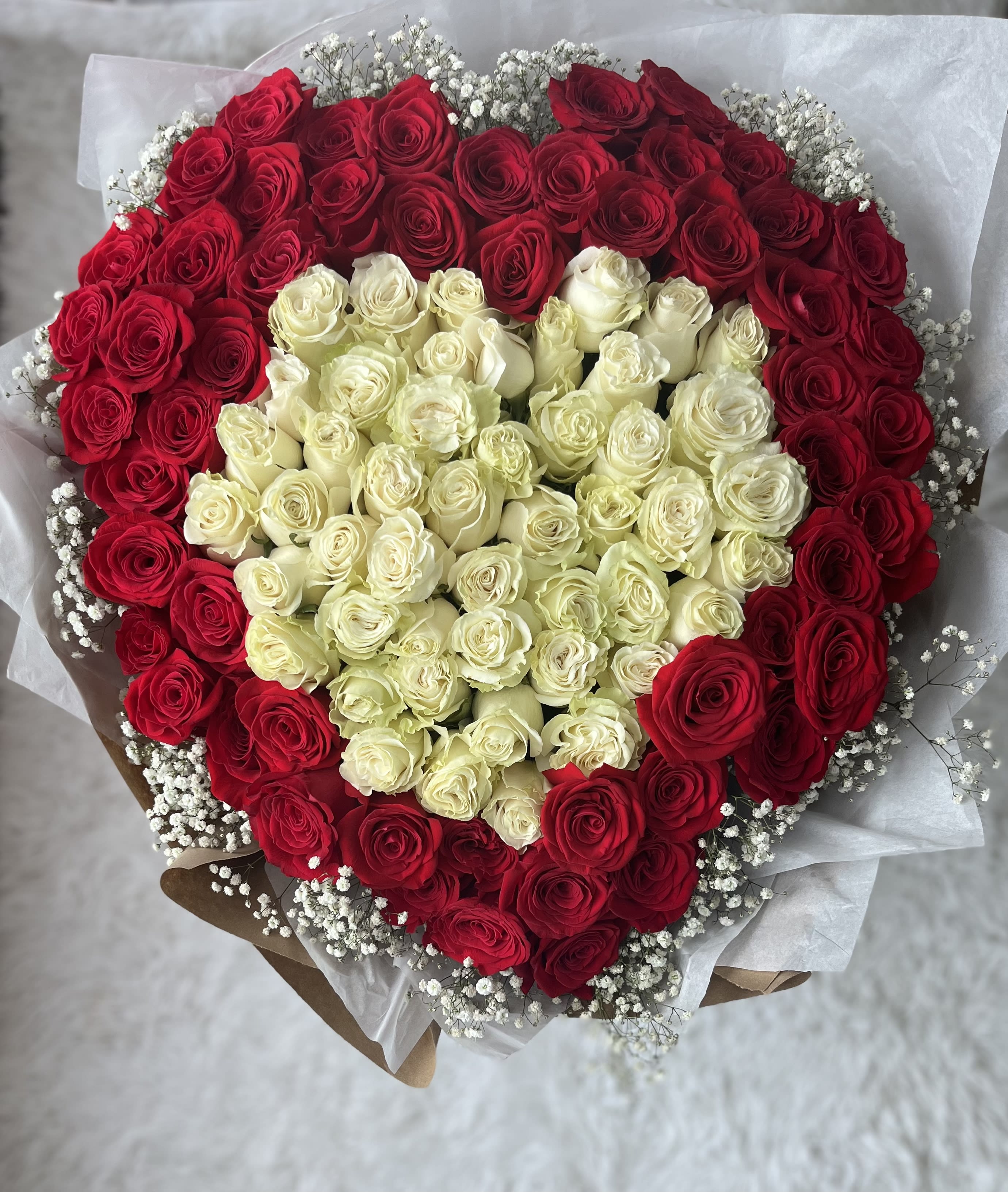 Heart-shaped bouquet of red and white roses with baby's breath