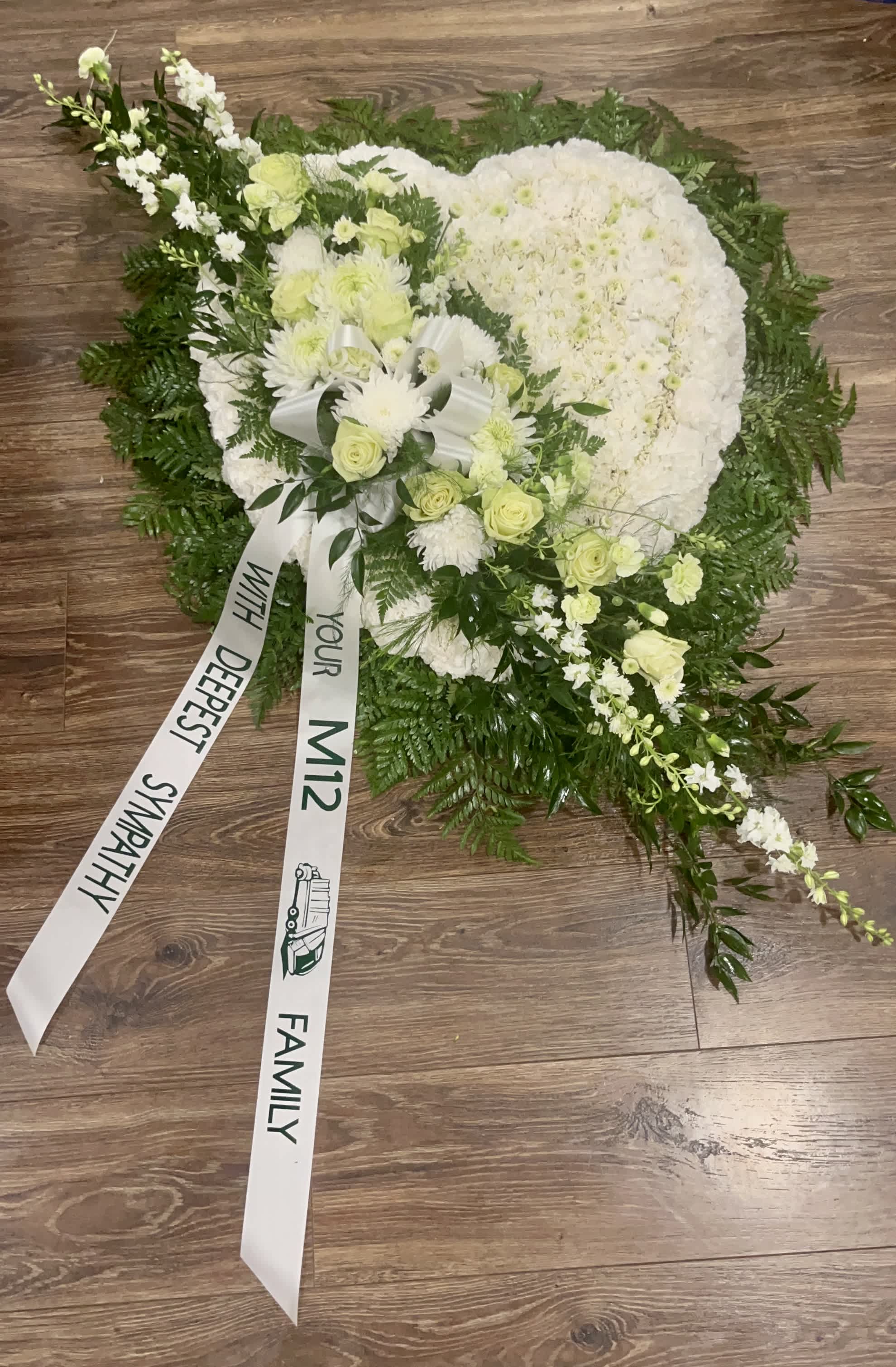 Always in our hearts  - This heart shaped wreath is a very loving way to celebrate your loved one. This funeral spray is pure and tranquil. Featuring a variety of white flowers and green palms this elegant funeral spray brings a feeling of peace &amp; love to it's surroundings. Please call us to let us know what color &amp; message you’ll like it personalized with before you place this order (845)366-6992 