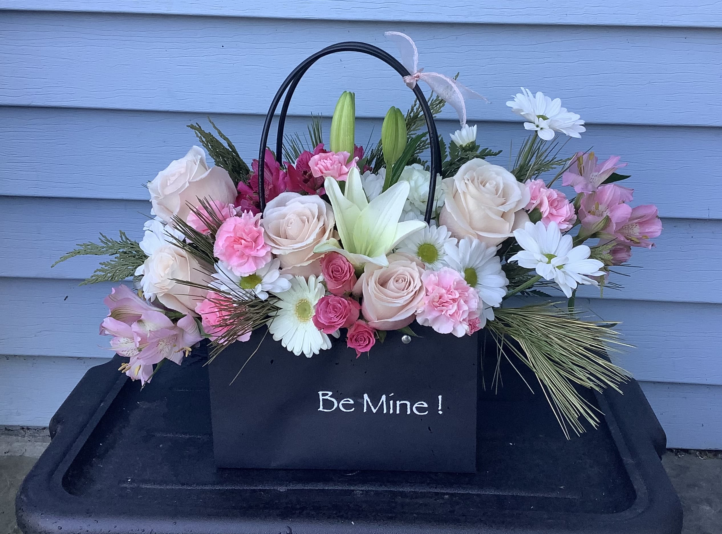 Pink and white flower arrangement in a black gift bag with "Be Mine!" text